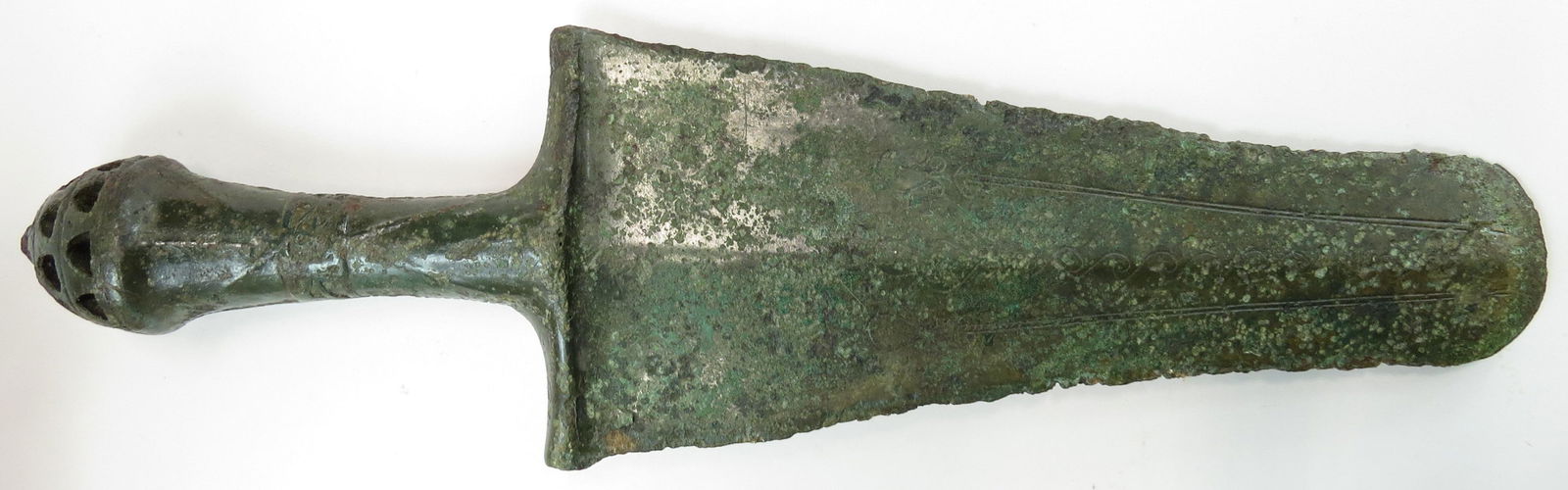 A LURISTAN SWORD: A rare form with conical, pierced pommel, the grip with decorative central band, the integral guard broad and well-defined. The tapering blade incised with lineal and curvilineal decoration. 9th-7th c