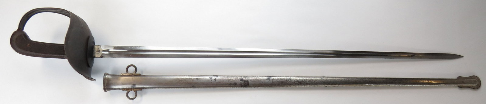 A U.S. M 1913 CAVALRY OFFICER’S SABER: The last pattern saber to be issued to American cavalrymen, designed by Lt. (later general) George S. Patton Jr. Characteristic black rubber grips, large, pressed steel guard and straight, double-edge