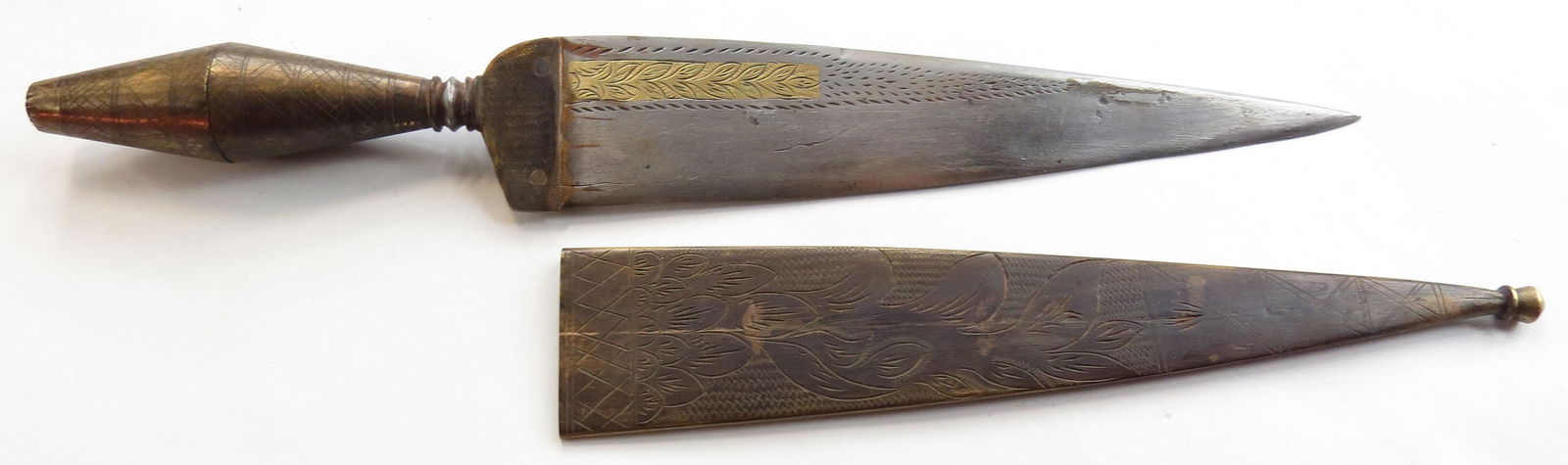 A MEDITERRANEAN DAGGER: Likely Spanish, the plug-form grip mounted in engraved brass with large bolster. Broad, single-edged engraved blade with substantial back edge, engraved and inlaid with brass. Brass sheath engraved en