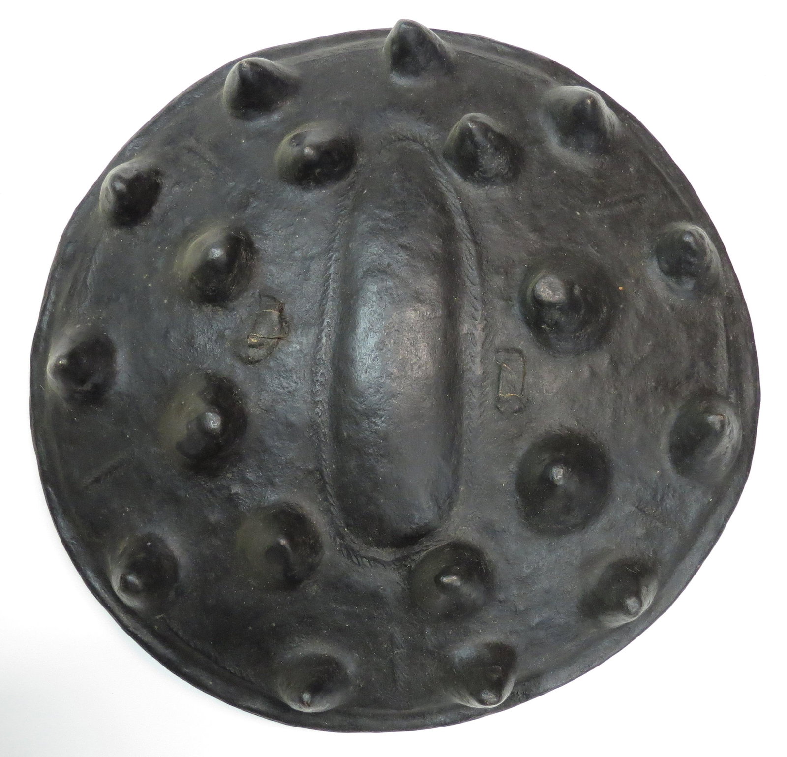 A RARE ETHIOPIAN SHIELD: Arussi People, of characteristic form, molded in thick hide with a series of large knobs and a broad central oval panel bordered by tooling, pigmented in a deep brown overall. The reverse with intact 
