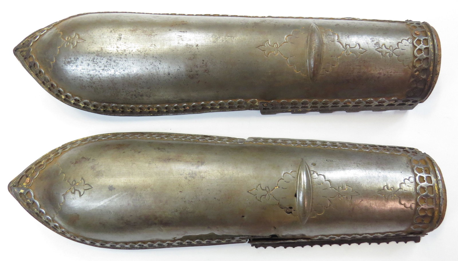 A RARE PAIR OF INDIAN BAZUBAND ARMGUARDS ARMOR: Likely Tanjore work, well-forged of steel with separately-applied pierced and profiled steel borders, with raised bosses and engraved motifs. 17th century. Cuffs lacking. Overall length 32.5cm. Condit