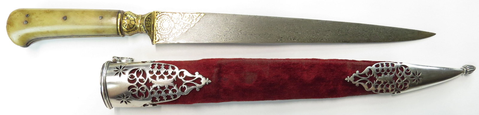 A FINE MUGHAL KARD DAGGER: The grips of figured pale green jade, with integral steel tangband and bolster heavily inlaid with gold. The straight, broad, single-edged blade with a large panel of gold inlay at either forte en sui