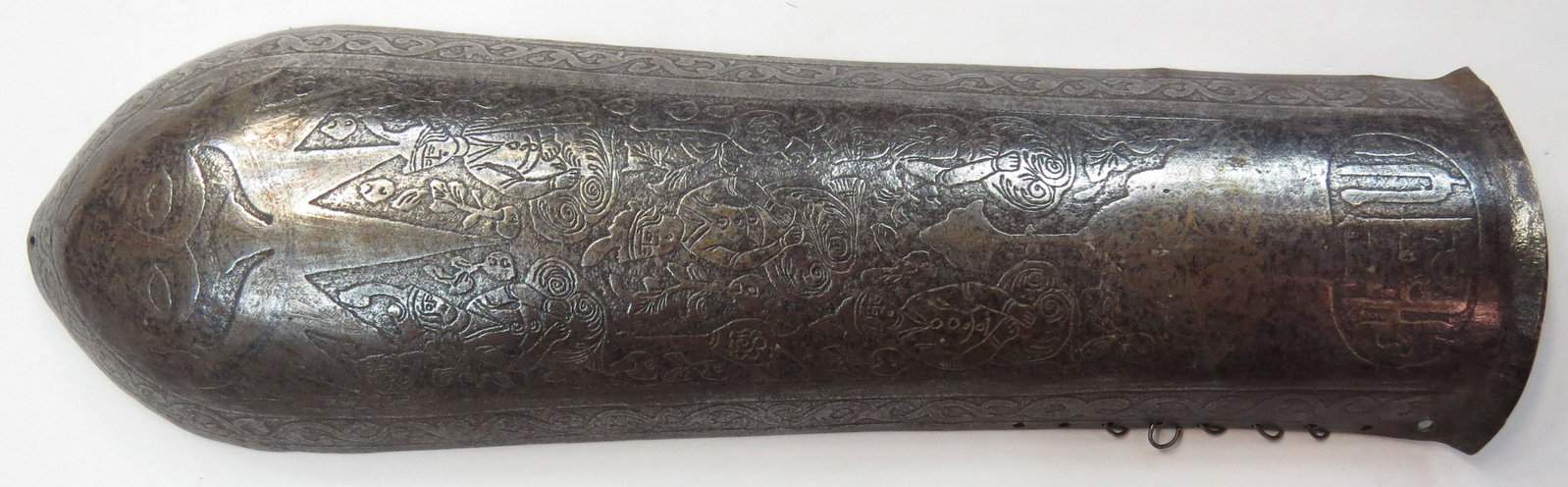 A PERSIAN BAZUBAND ARMOR ARMGUARD: Qajar Dynasty, raised from a single plate and deeply etched overall, with gold inlay. Mid-19th century. Worn overall. Overall length 31cm. Condition III