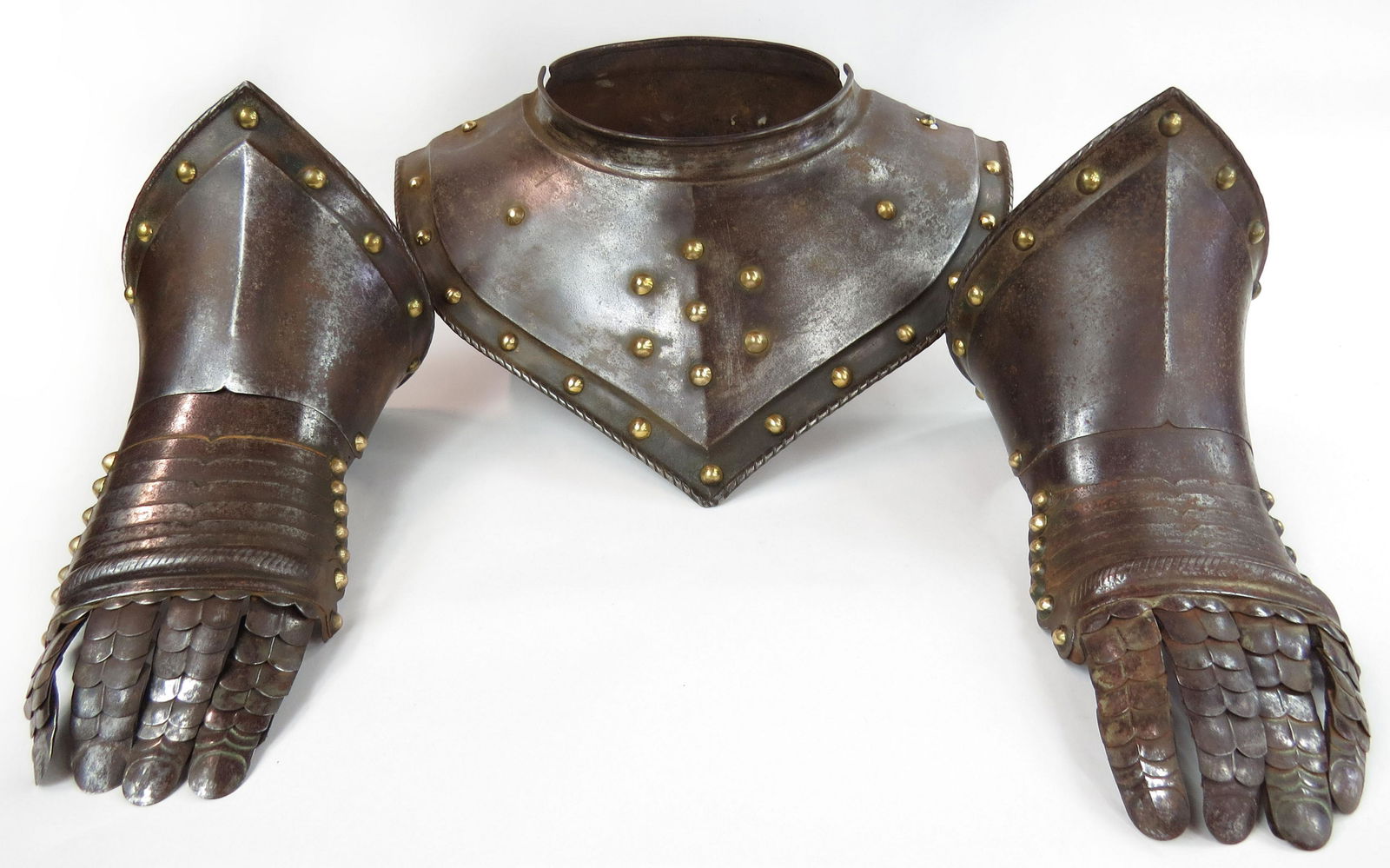 A SET OF EUROPEAN ARMOR GORGET AND GAUNTLETS: Very well wrought pieces of armor, likely German. The gorget with central ridge and embossed borders with rolled and roped edges, and set with numerous brass studs, with its en suite pair of gauntlets