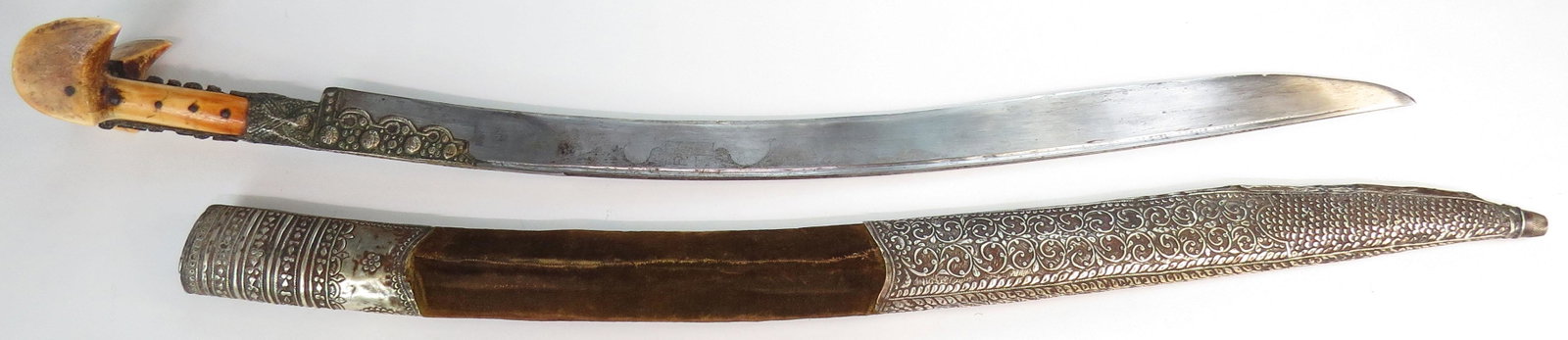 AN OTTOMAN YATAGHAN SWORD: With massive walrus grips of Balkan form, the elaborate tangband and bolsters gilded and set with corals. The broad, single-edged recurved blade with narrow fuller, with worn silver inlay cartouche. T