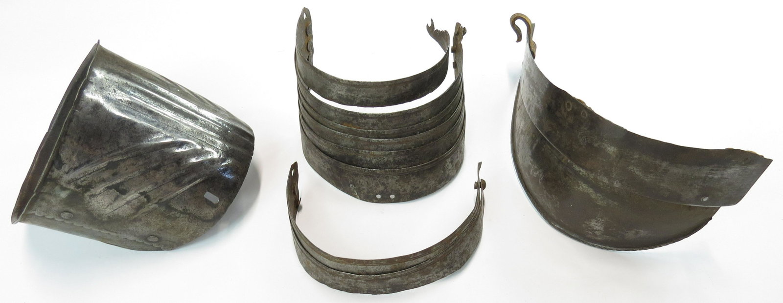A GROUP OF ITALIAN ARMOR ELEMENTS: Comprising parts of a spaulder and rerebrace, displaying engraved borders, and embossed work. 16th-17th century. As found. Height of the largest 12.6cm. Condition V