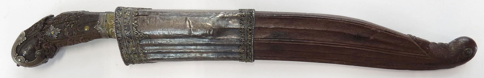 A FINE SINHALESE PIHA KAETTA DAGGER: An excellent example of characteristic form, the intricately-carved ebony grip with applied profiled and engraved silver plaques in elaborate scrollwork motifs. The brass forte inlaid with silver and