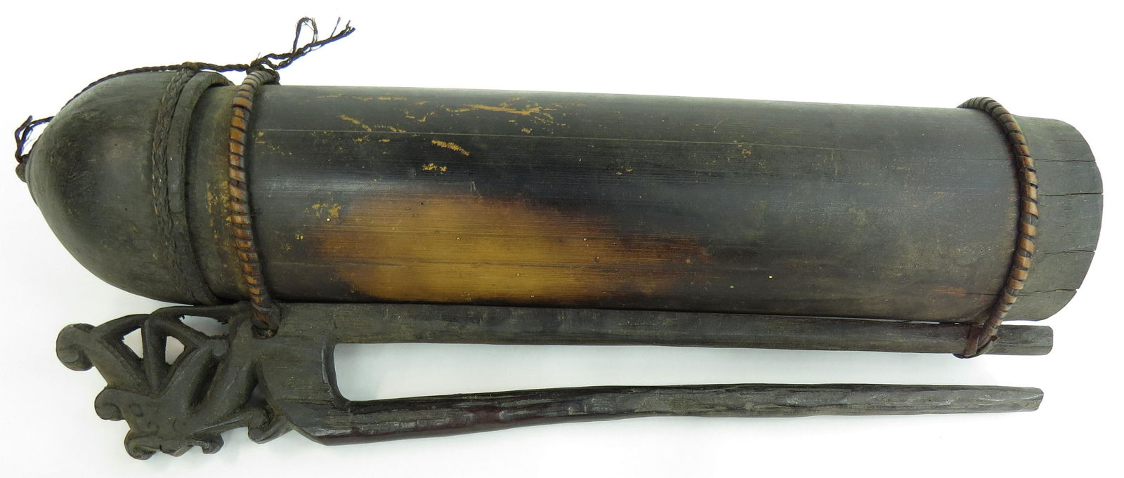 A DAYAK DART CONTAINER: Made from a section of bamboo with fitted cap, and WELL-carved wooden hook retained by rattan. Early 20th century. Worn. Overall length 35cm. Condition III