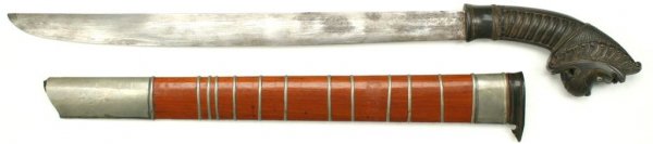 A Javanese Klewang Sword: The horn grip elaborately carved, the pommel formed as a lion's head with inlaid eyes, mounted with a single-edged blade. Scabbard of red-lacquered wood with horn and engraved silver locket and chape,