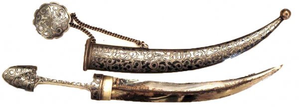 A Caucasian Child's Kindjal Dagger: Probably Kubachi work, the silver hilt and scabbard finely proportioned, engraved and nielloed. Curved, double-edged blade with central ridge, scabbard retains its suspension system with nielloed-silv