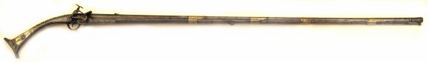 An Albanian Tanchitsa Musket: A rare form, the stock sheathed entirely in engraved iron, set with brass and mother-of-pearl plaques and silver studs. The miquelet lock with maker's mark struck on the lockplate and an eagle engrave