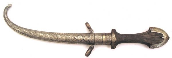 A Moroccan Koumiyya Dagger: The wooden grip and scabbard with heavily engraved silver, with curved single-edged blade. Late 19th - early 20th century. Overall length 42 cm, blade 22.1 cm. Condition I