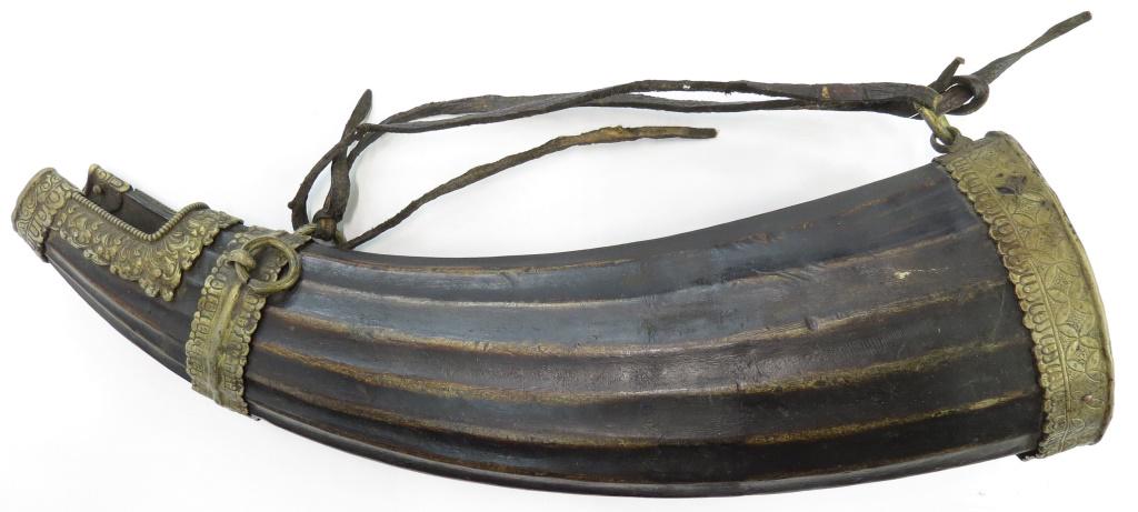 A TIBETAN POWDER HORN: A massive example used for filling smaller powder horns, well carved of water buffalo horn with engraved brass mounts. 18th-19th century. Overall length 47cm. Condition III