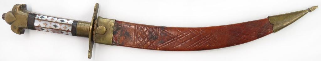 AN ANGLO-INDIAN DAGGER: With brass mounts and grip inlaid with mother of pearl, the lightly curved, etched blade maker-marked at the forte. In its leather sheath with brass mounts. Late 19th – early 20th century. Well worn