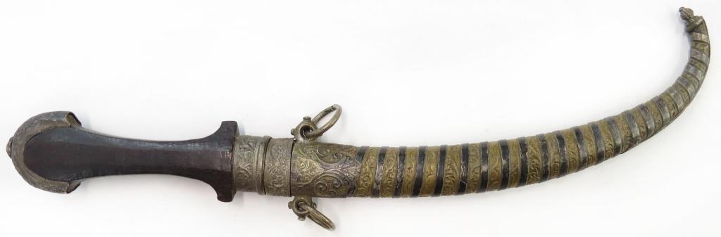 A MOROCCAN KOUMYA DAGGER: Of above average quality, the obverse of silver and brass and engraved overall. The curved blade with long back edge. 19th -20th century. Worn. Overall length 37.5cm. Condition II