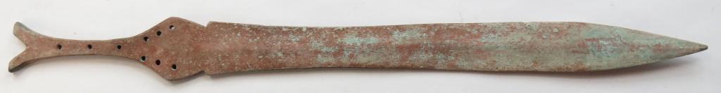 A BALKAN BRONZE-AGE SWORD: Of characteristic Naue II Group I form with bifurcate pommel and flanged guard, the waisted grip and stepped bolster indicating a Balkan variant. The blade expanding toward the tip, with slight centra