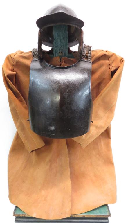 A RARE ENGLISH CIVIL WAR ARMOR: Comprising a helmet with broad peak and neck with ear flaps and original lining intact, together with a massive breastplate with shoulder tabs and straps intact. Accompanied by a modern leather buff c
