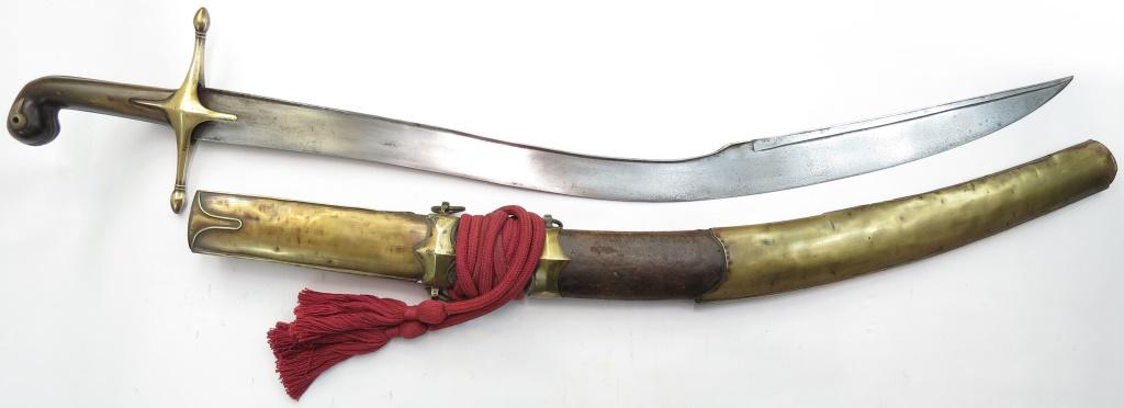 AN OTTOMAN PALA KILIC SWORD: Of classic form, the hilt with horn grips and large brass guard. The broad, T-section blade showing good forging with distinct yelman or back edge. In its leather-covered wooden scabbard with large en