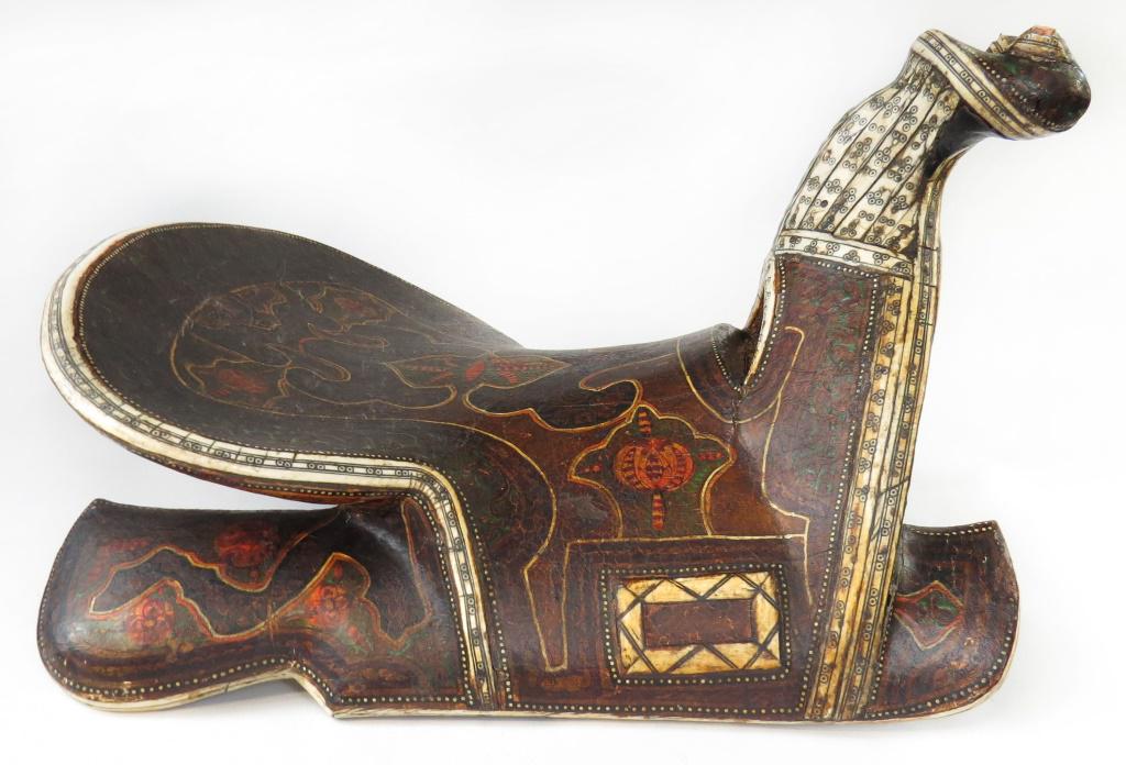 A FINE AND RARE BUKHARA SADDLE: An iconic form, finely carved entirely of wood with pronounced bifurcate pommel and raised, rounded cantle. Elegantly covered in polished hide polychromed overall in characteristic dramatic vegetal an