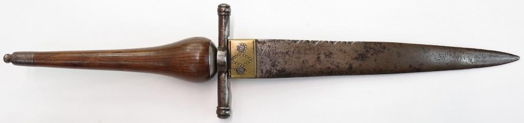 A SPANISH PLUG BAYONET DAGGER: With iron guard, ferrule and pommel cap and elegant turned wood and grip. The double-edged blade with brass ferrule and profiling. 18th century. Overall wear. Overall length 38cm. Condition III