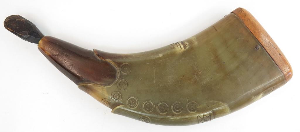 A CONTINENTAL POWDERHORN: Scandinavian, of flattened and profiled horn with birdseye stamps. 18th-19th century. Plug replaced. Overall length 23cm. Condition II