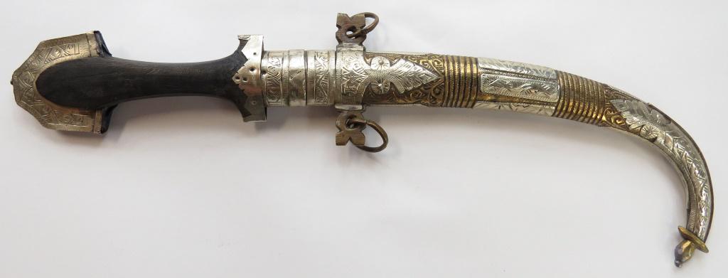 A MOROCCAN KOUMYA DAGGER: With crested pommel, the scabbard engraved overall, with curved, single-edged blade and wooden grip. 20th century. Overall length 41.5cm. Condition II