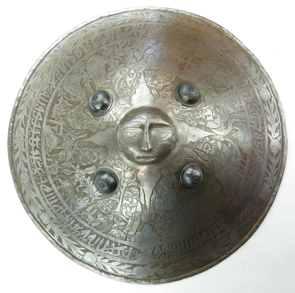A PERSIAN SIPAR SHIELD: Handwrought of steel and etched with characters from Persian mythology, the center embossed in high relief, representing the sun. 19th - 20th century. Diameter 58cm. Condition II