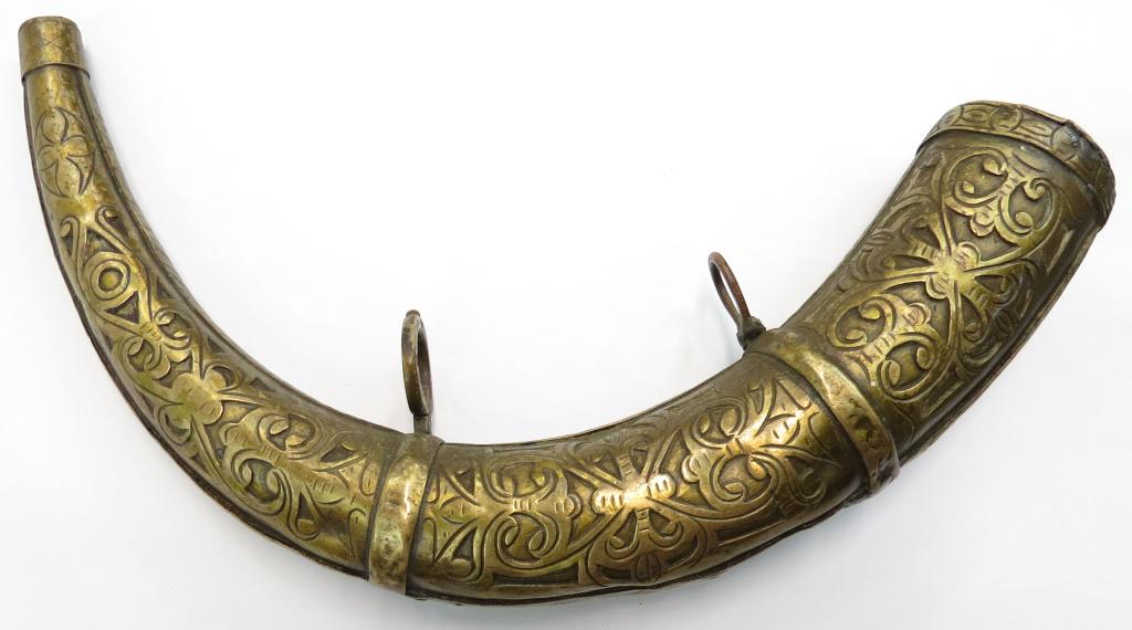 A MOROCCAN POWDERHORN: An earlier example, covered in brass and elaborately engraved overall with characteristic vinework. First half of the 19th century. Worn. Overall length 302cm.Condition II