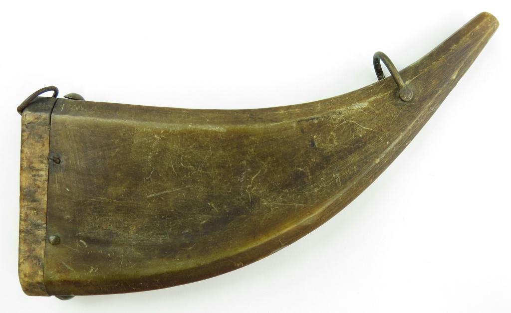 A CONTINENTAL POWDERHORN: Of pressed horn with chamfered edges, decorated with brass studs. 19th century. Worn. Overall length 23.5cm. Condition III