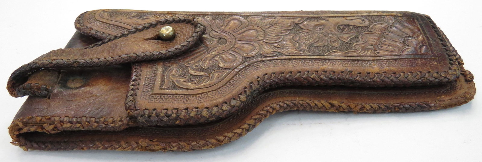 A MEXICAN REVOLUTIONARY-ERA HOLSTER: Of leather, finely tooled with flowering vinework, with safety strap intact and laced borders.Appears to fit the Colt M 1911 .45 pistol, which was extremely sought after by followers of Pancho Villa. 