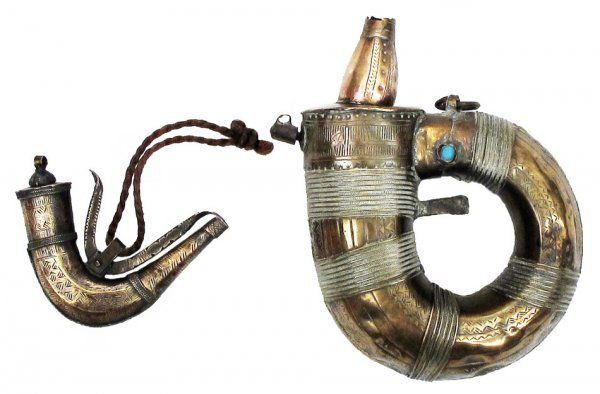 AN OMANI PRIMING FLASK AND POWDERHORN SET: Both of typical form, the faceted brass bodies with engraved motifs and seamed in filigree, the horn with a turquoise. Brass cutoffs. First half of the 19th century. Very minor dents. Overall length o
