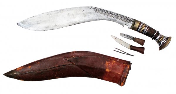 A NEPALESE SHORTSWORD KUKRIE: Of characteristic form, with wooden grip flared at the pommel and inlaid with soft metals in geometrical designs. The massive blade with chiseling at the spine, and choil at the forte. In its leather 