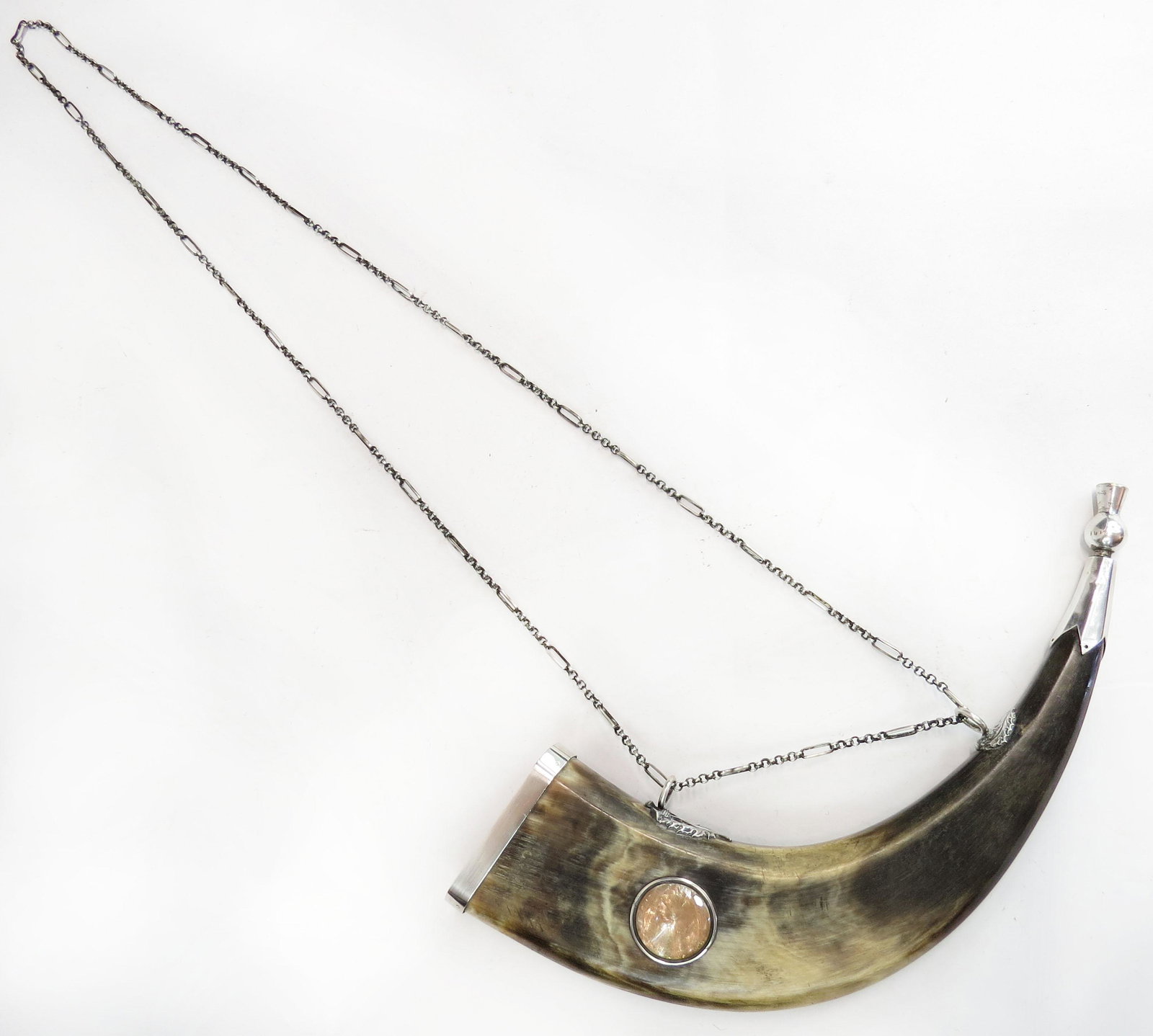A RARE SCOTTISH POWDERHORN: The polished, flattened and faceted horn body mounted in silver, set with a faceted glass gem, the spout with thistle-form terminal containing a pricker, the suspension mounts finely modeled as double