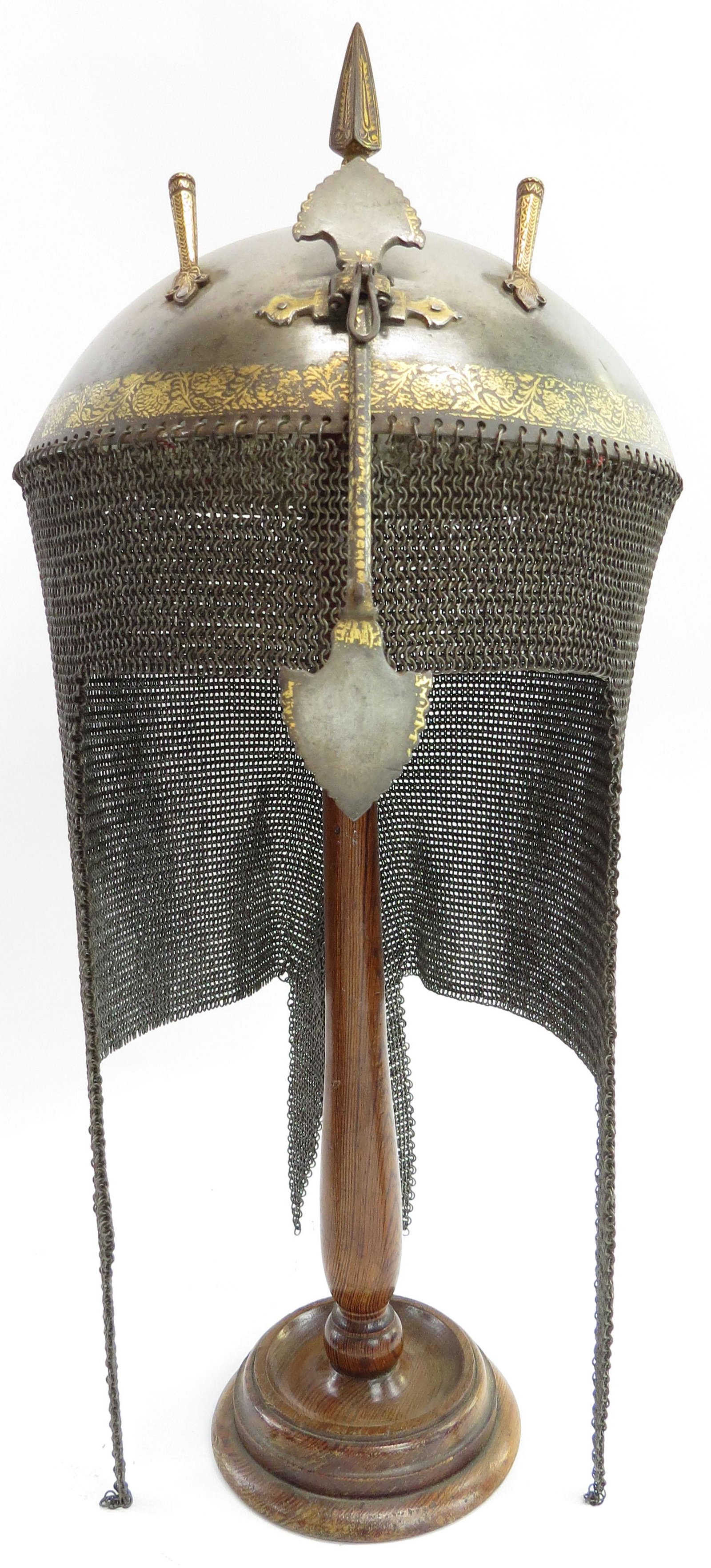 AN INDIAN TOP HELMET: Mughal work, an earlier example than usually encountered. Finely wrought of wootz steel, the hemispherical bowl with spike finial, captured nasal bar and plume tubes, all embellished with flowering vi