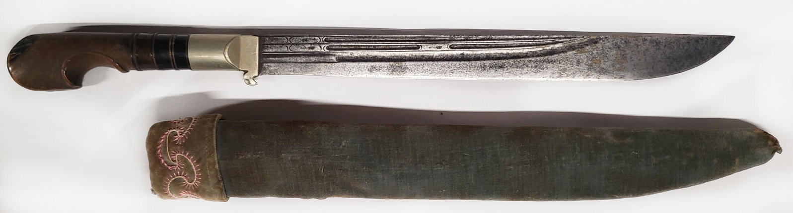 AN OTTOMAN SURMENE DAGGER: A large example with characteristic eared horn grip and deeply bellied, finely fullered blade. In its embroidered velvet-covered wooden scabbard. Second half of the 19th century. Worn. Overall length 