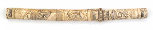 A JAPANESE VOTIVE TANTO DAGGER: The bone mounts carved with samurai figures, the blade with brass habaki. Early 20th century. Overall length 38.8 cm. Condition II