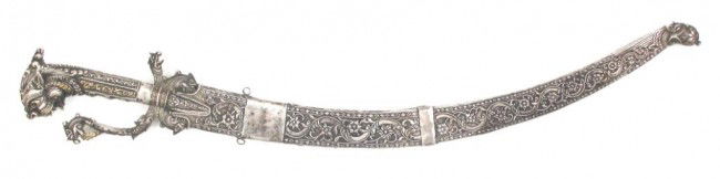 A SRI LANKAN KASTANE SWORD: Of classic form, the silver and gilt hilt elaborately embellished with scrollwork, the pommel a fully-modeled makara head, the knuclebow and guard likewise terminating in monster heads. The curved, si