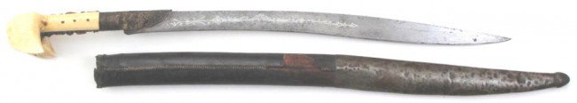 AN OTTOMAN YATAGHAN SWORD: The massive walrus grips of Balkan form, with gilded tangband set with corals and bolsters and single-edged recurved blade with silver inscriptions, 1189 [1775 c.e.] WORK OF AL HAJ ABDUR____[?] OWNER 