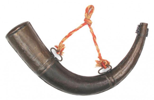A MOROCCAN POWDERHORN: The iron body with stamped and engraved brass mounts, and retaining a section of woven cord. Early 20th century. Generally wear. Overall length 35 cm. Condition III