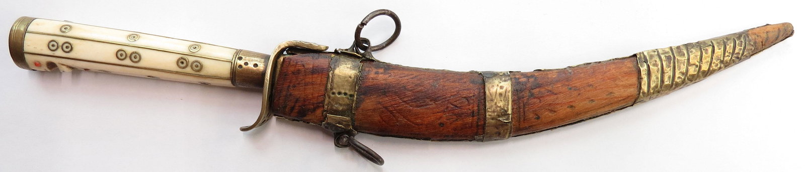 A RARE BOSNIAN DAGGER: The antler grip well-inlaid with brass, the terminal carved with a very rare human face, the eyes of coral. Broad, single-edged blade with an engraved panel at each forte and double-edged at the tip.