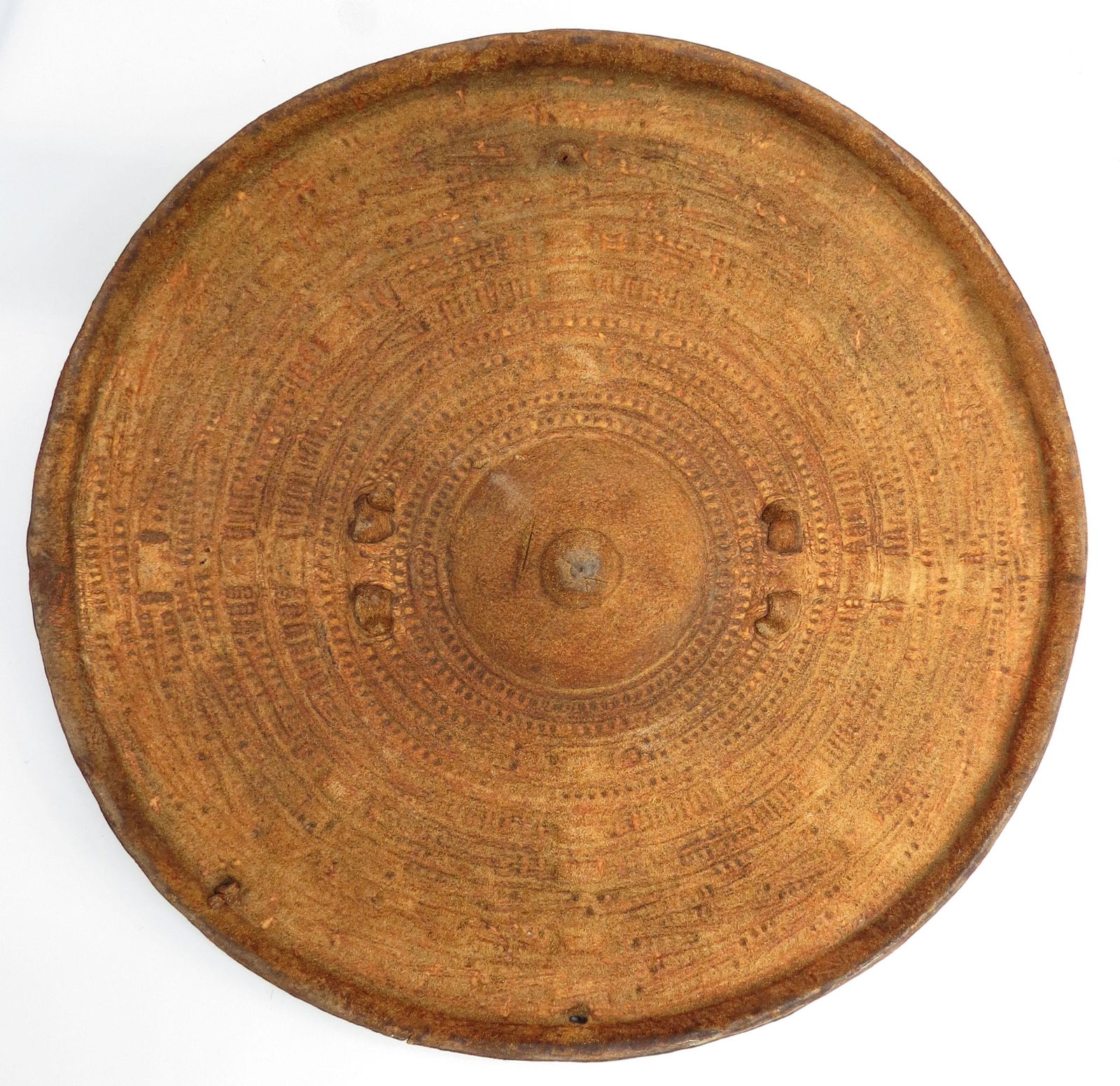 AN ABYSSINIAN HIDE SHIELD: Of molded rawhide with separately-applied grip, the obverse with characteristic minute geometrical tooled motifs overall. Mid-19th century. Diameter 32cm. Condition II