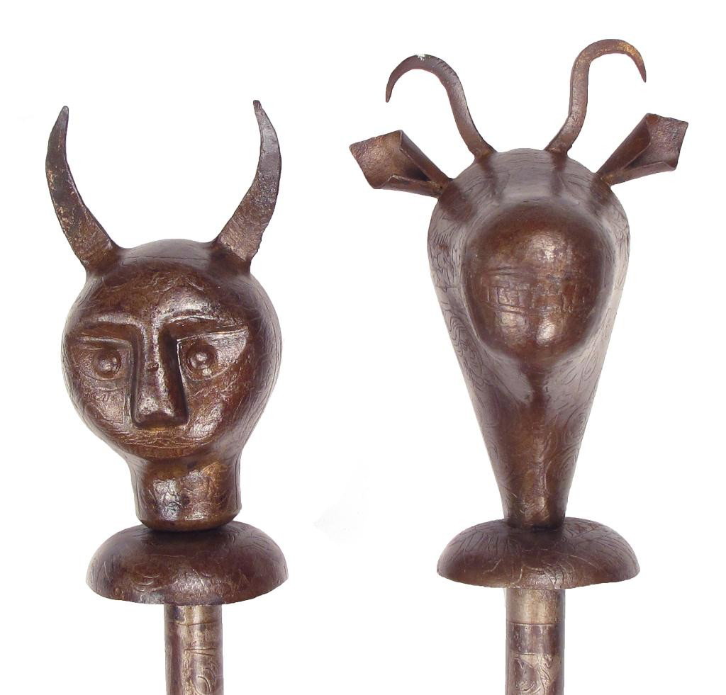A PAIR OF QAJAR PERSIAN MACES: Of steel, the first formed as a bull’s head with fully-modeled ears and horns, with etched eyes, nose and teeth, as well as characters from the Book of Kings. The second in the form of a devil’s h