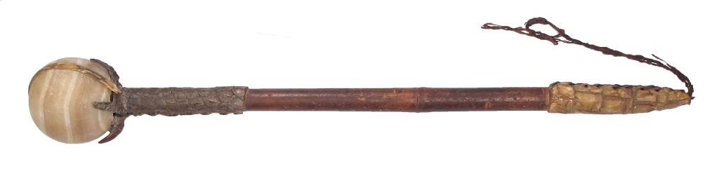 AN IMPORTANT SUDANESE COMMANDER’S MACE: The spherical head of polished brown alabaster with undulating bands of cream, held to the wooden haft by a crocodile’s forelimb terminating in five clawed extremities, and bound with a strip of cro