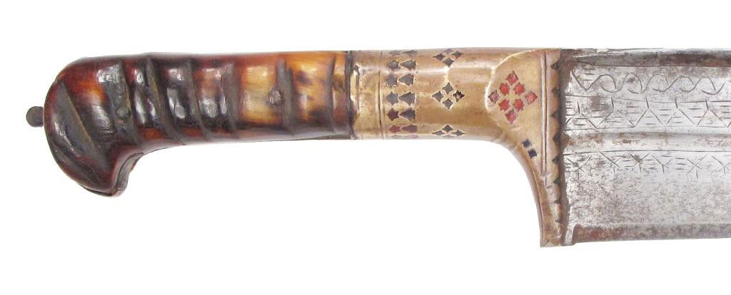 AN AFGHAN SALAWAR SHORTSWORD: Also known as a Khyber knife, the blade of characteristic form with T-back, quite broad and engraved at the forte. The scalloped brass bolsters finely pierced in geometrical designs and filled with re