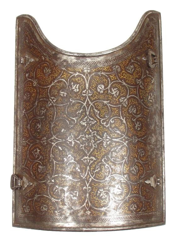 A FINE NORTH INDIAN ARMOR PLATE: Forged of steel with rounded rim, the surface lavishly inlaid in gold scrollwork intertwined with silver flowering vines. With hinged buckles. First half of the 19th century. Light wear, two buckles l
