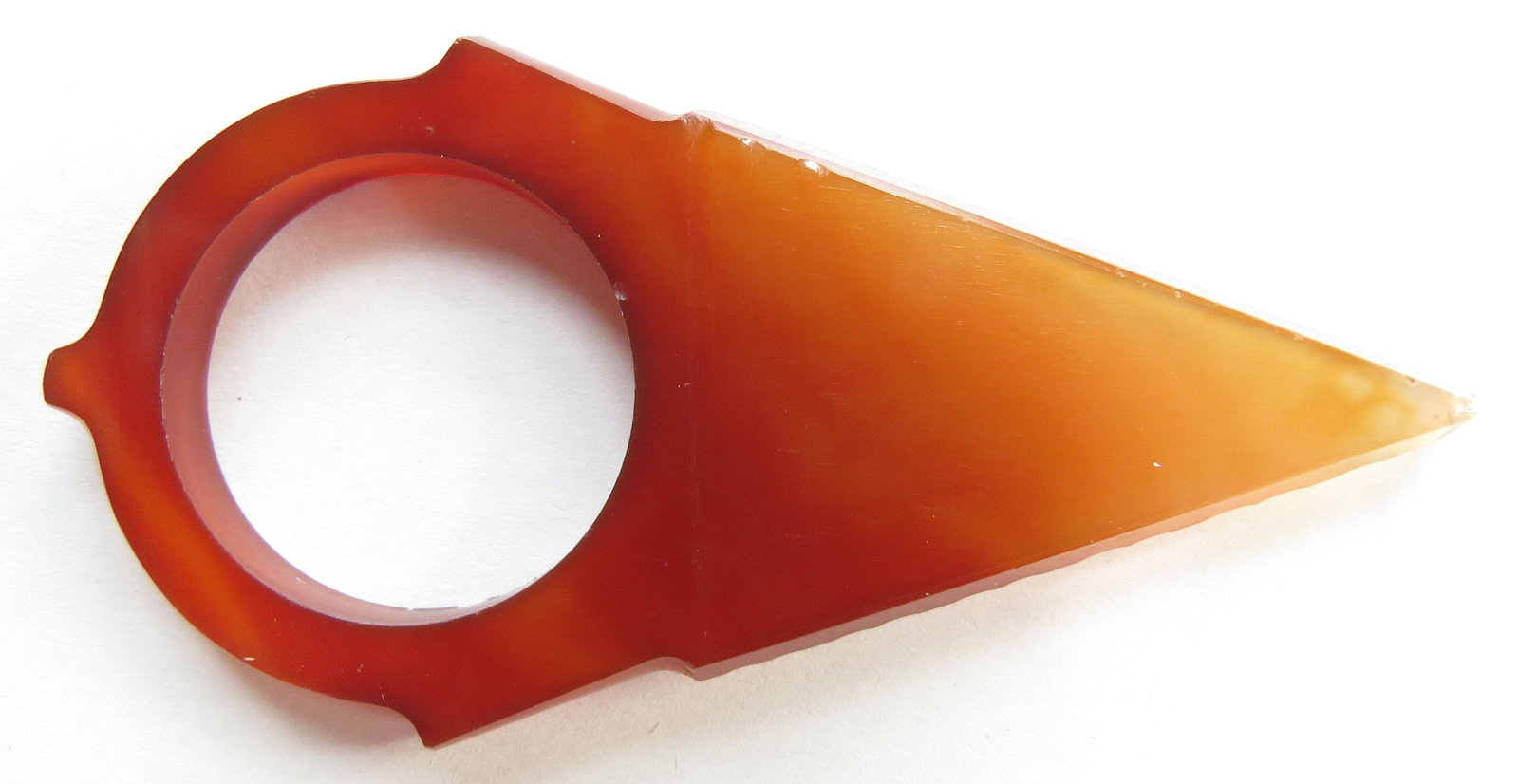 A TUAREG ARCHERS RING: Of characteristic triangular form, handground of carnelian agate and well-polished. 19th c. Overall length 6.6cm. Condition I