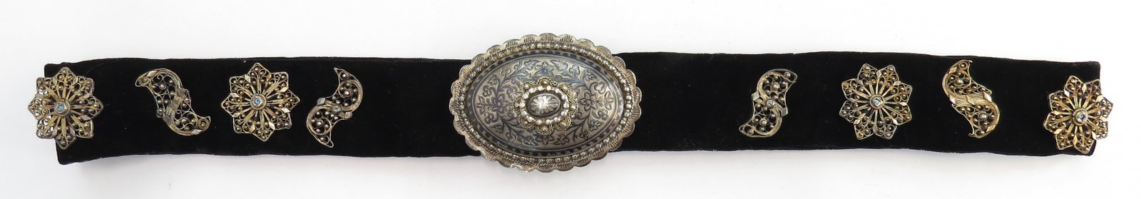 A RARE ARMENIAN SILVER BELT: The large, oval buckle wrought in silver of oval form with scalloped and beaded border with raised central plaque embellished with engraved and nielloed flowering vinework, parcel gilded and struck on
