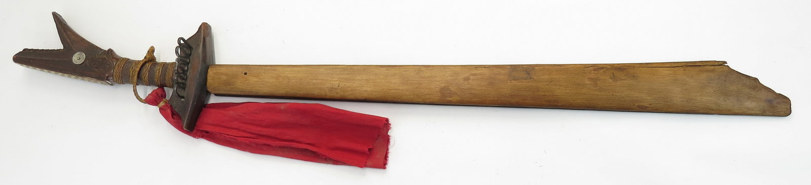 A PHILIPPINES KAMPILAN SWORD: Moro People, a massive example, the hardwood hilt with fine and elaborate carved decoration overall, retaining its iron guard and rattan band securing a red cloth munsala. The handwrought blade showin