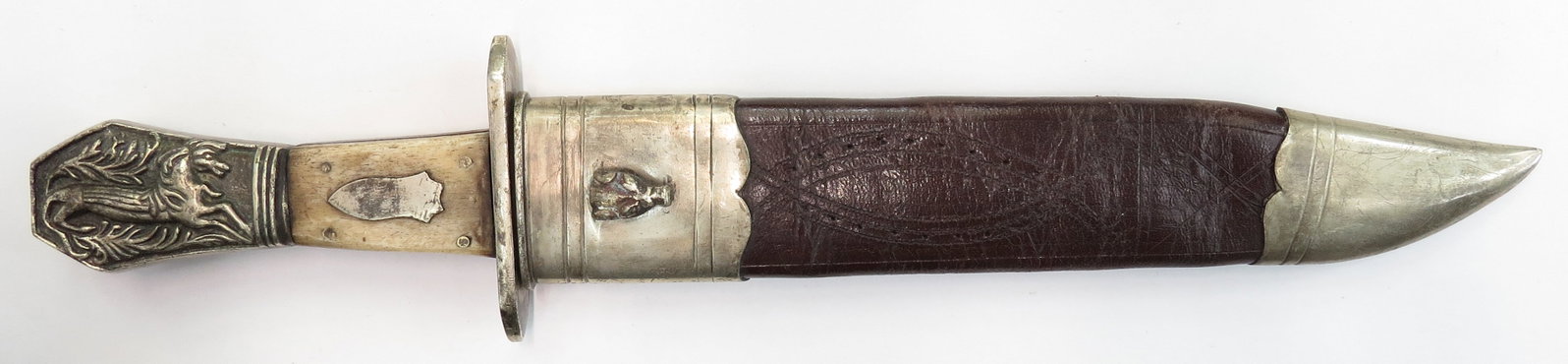 A SHEFFIELD BOWIE KNIFE: A well-made copy, with coffin-shaped pommel embossed with a running horse on either side, straight guard and shield-shaped escutcheons on the grip, all white metal, the grips of bone. The robust blade