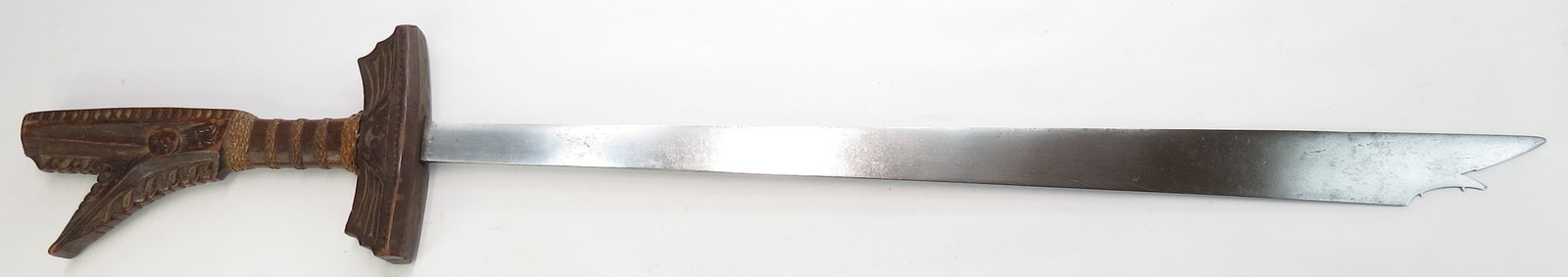 A PHILIPPINES KAMPILAN: Moro People, likely Maguindanao. A massive example with finely-carved hilt of hardwood with woven rattan bands. The handwrought blade showing evidence of layering, with profiled tip and spikelet intac